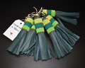 A leather key holder with green  tassels and Maasai beadwork, displayed against a dark background with a 'Handmade in Kenya' tag.